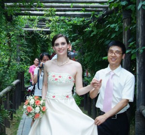 Western wife and Chinese husband on wedding day, walking under a trellis